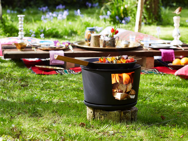 small cooking fire pit with logs on fire and skillet pan on top