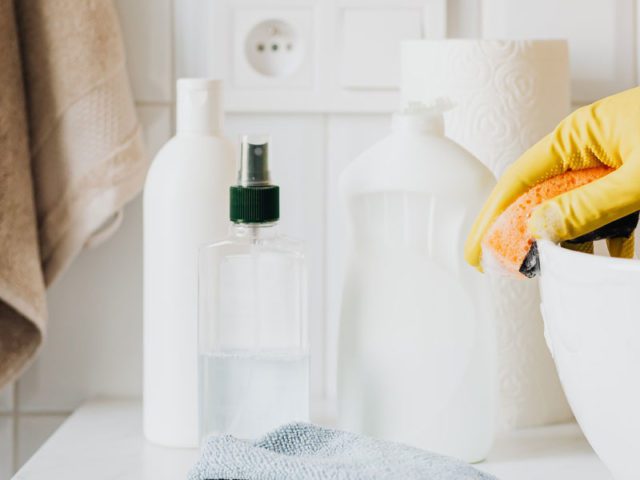 Cleaning the bathroom sink wearing yellow rubber gloves