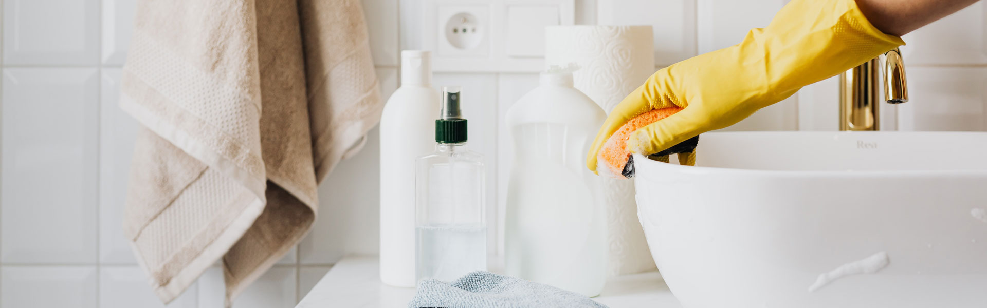 Cleaning the bathroom sink wearing yellow rubber gloves