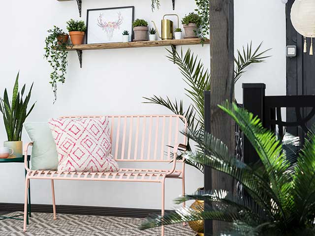 Pink garden bench with garden shelfie packed with plants