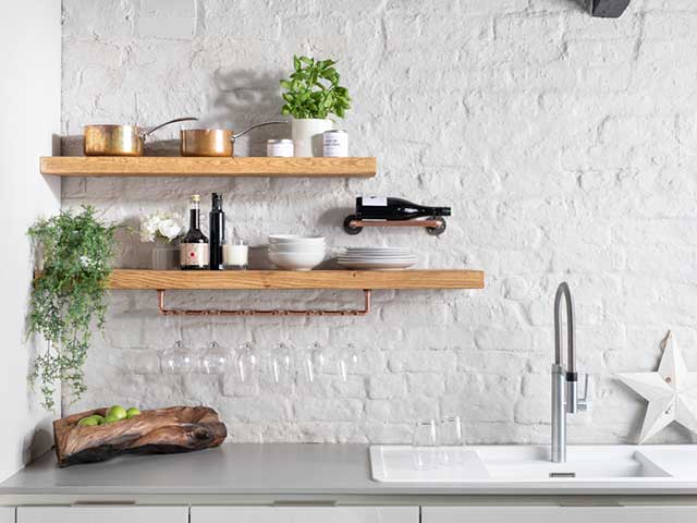 Wooden kitchen shelves against white tiled wall