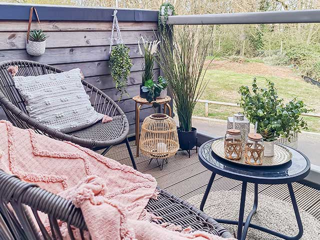Wooden decking on balcony with hanging plants black wicker chairs and rattan accessories