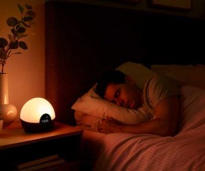 Man asleep in bed with sleep tech Lumie light on night stand 