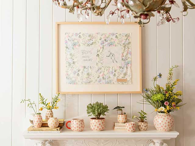 Planters on white fireplace on white panelled wall with frame 