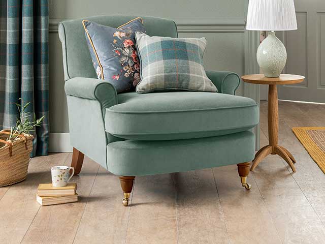 Armchair with cushion and gold legs on wooden floor