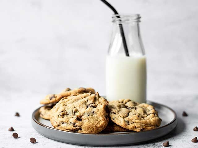Cookies on grey tray with glass of milk which are third of Britain's most-loved bakes