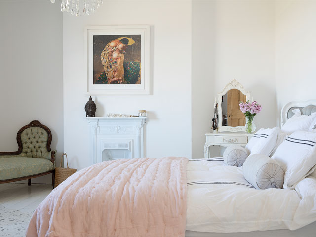 Traditional cottage bedroom painted white with period fireplace and second-hand furniture