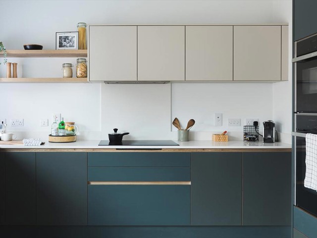 Modern kitchen with handleless green base units and handleless stone wall units