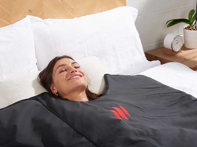 Woman relaxing in bed underneath infrared blanket sleep tech