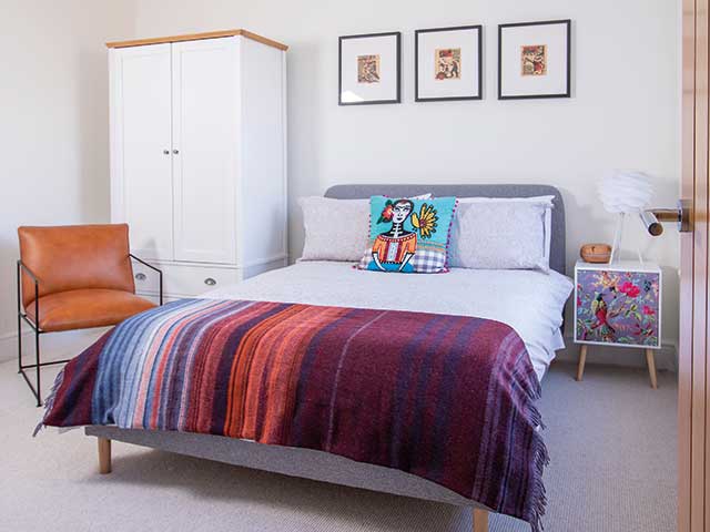 Master bedroom of new build house with white furniture and pops of vibrant colours