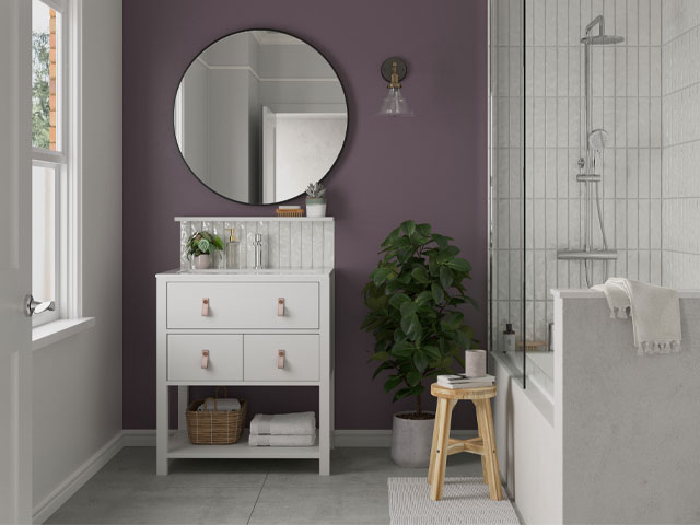 Purple feature wall in a bathroom with white tiles, white vanity unit and large round mirror