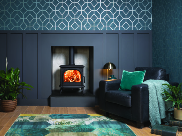 deep blue panelled wall with blue geometric wallpaper and blue/green rug
