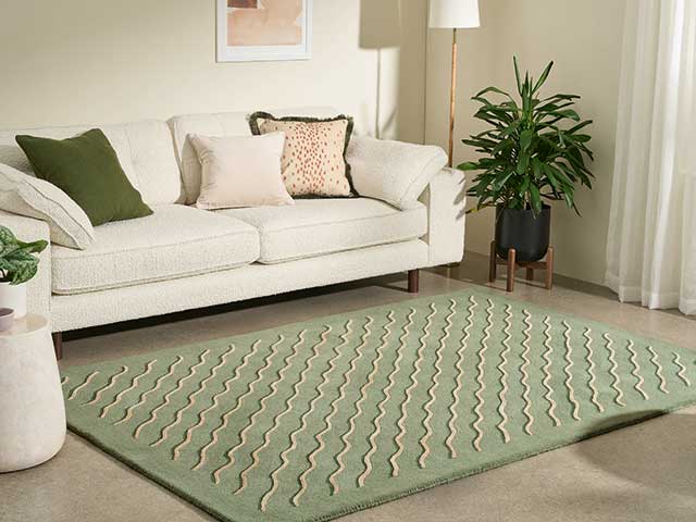 Bellisima tufted green rug in living room with cream sofa and beige carpet