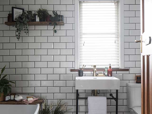 White tiled tropical bathroom with shelfie, freestanding bath and basin