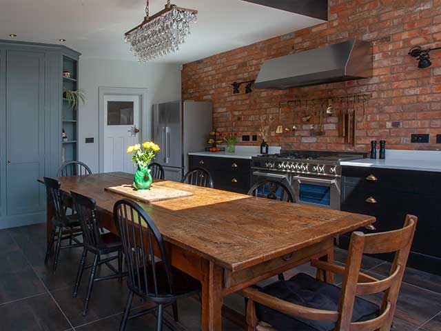 Wooden dining table with chandelier light in industrial style kitchen