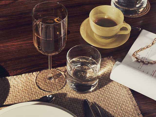 Crystalline glasses on wooden table with woven placemat from Zara Home AW21 collection