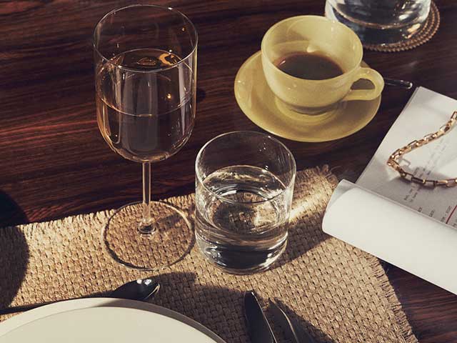 Crystalline glasses on wooden table with woven placemat from Zara Home AW21 collection