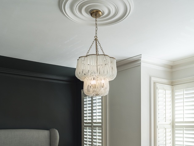 white scalloped chandelier with beads in living room with dark grey walls