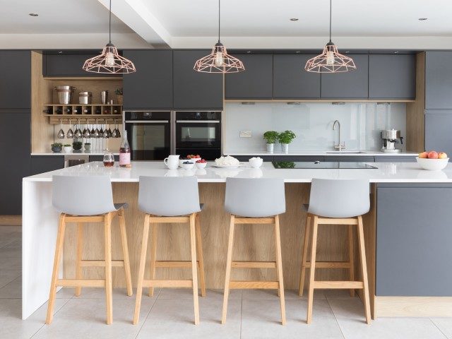 large kitchen island in modern family kitchen with bar stools and pendant lights