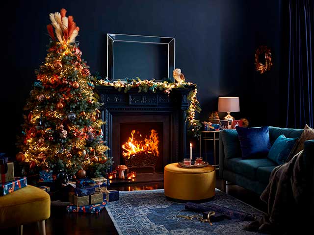 Christmas decorations on tree with roaring fire in cosy living room