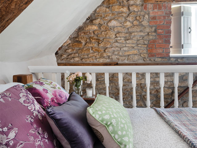 cosy cottage bedroom in the eaves with beautiful beams and exposed brick wall