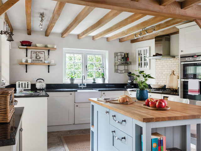 cottage kitchen makeover: the ceiling beams remain and the cupboards have been painted white