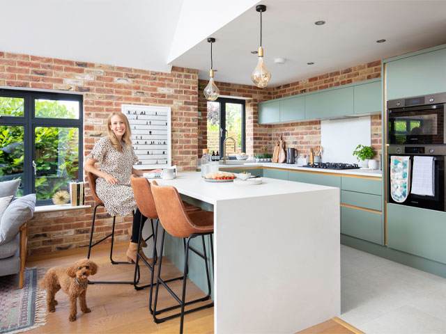 Cassie Lester in her remodelled kitchen with faux exposed bricks, kitchen island and dog, Maxie