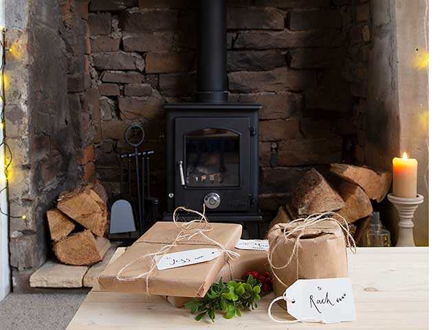 Woodburning stove with brown papered presents on wooden table