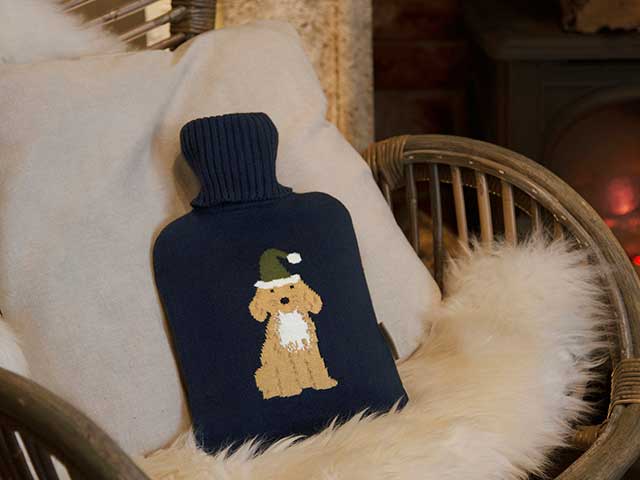 Cosy season Christmas hot water bottle in armchair with fluffy blankets