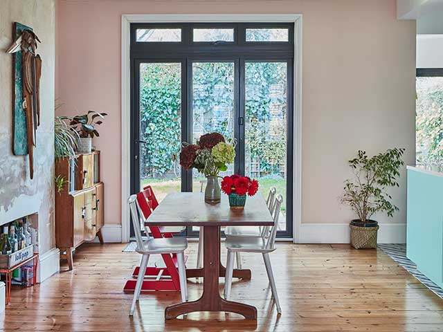 pink walls and green cabinets in a colourful kitchen diner with Miami vibes