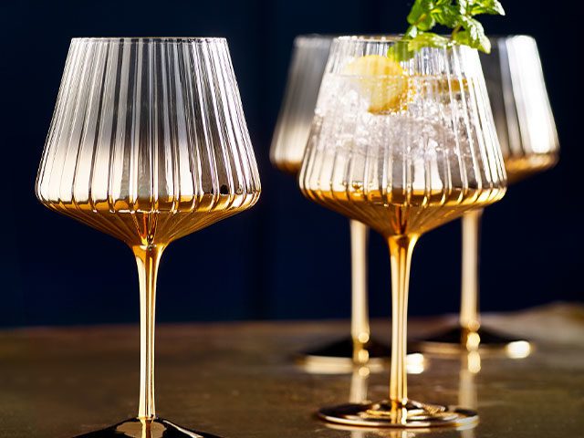 gold stem wine glasses on a copper tabletop with navy walls in the background