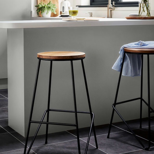 Industrial-style stackable stools with wooden seat and black-metal legs on a tiled floor