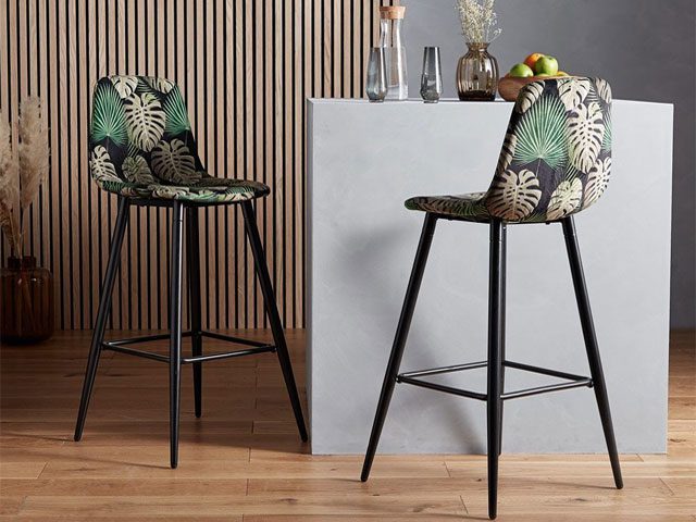 velvet bar stools with jungle-print seats and black legs in a kitchen with wall panelling and kitchen island