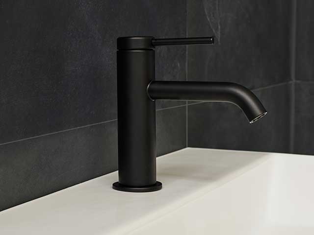 Black matte sink taps on white basin with black tiles behind