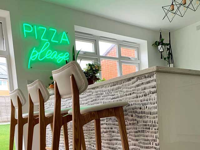 Neon sign pizza please in kitchen bar area