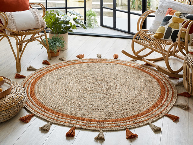 70s boho fringe rug in living room with laminate floor and doors opening to courtyard