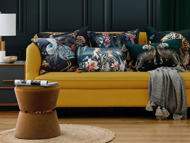 cushions in mixed prints and animal prints piled up on a mustard sofa