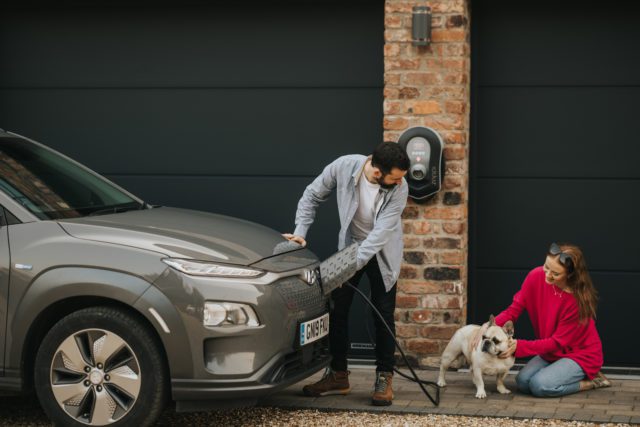 electric car charging at home with small ev charger mounted on a brick wall