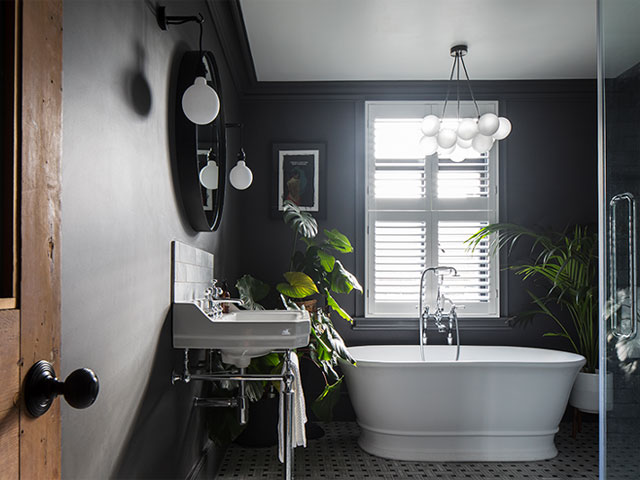 dark grey bathroom with plants, freestanding bath and bubble chandelier
