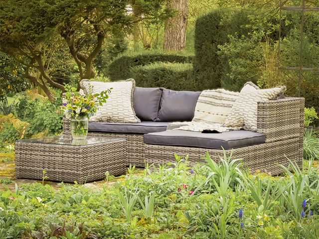Three-piece rattan garden sofa lounge set with green cushions in verdant garden