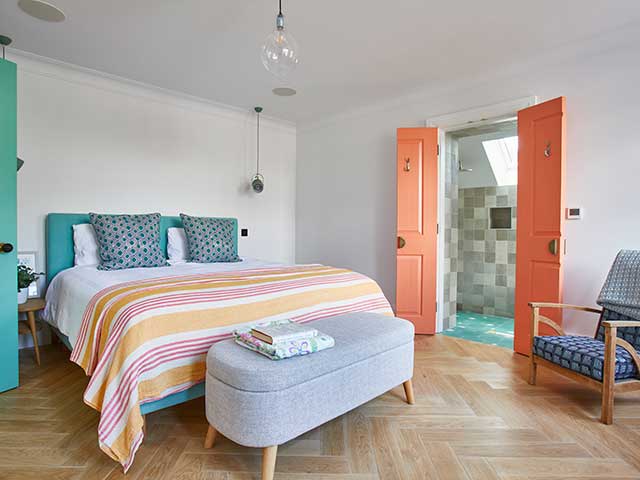 white bedroom with wooden floors and turquoise and coral accent colours