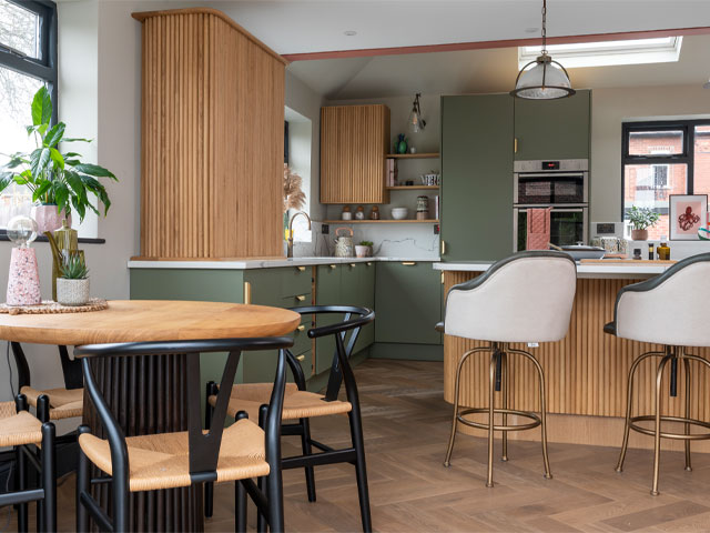 open-plan kitchen-diner with green cabinets and fluted wood joinery