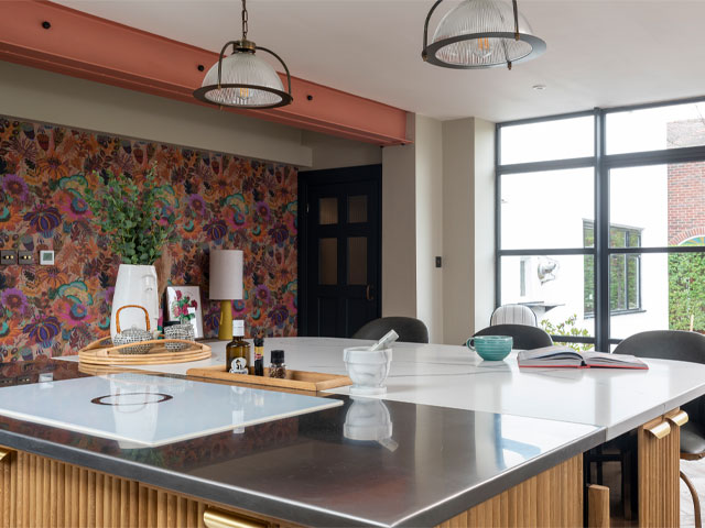 large open-plan kitchen-diner with exposed steel beam and bold floral wallpaper