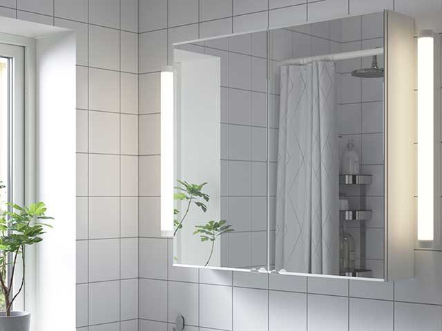 mirrored bathroom cabinet in white tiled bathroom