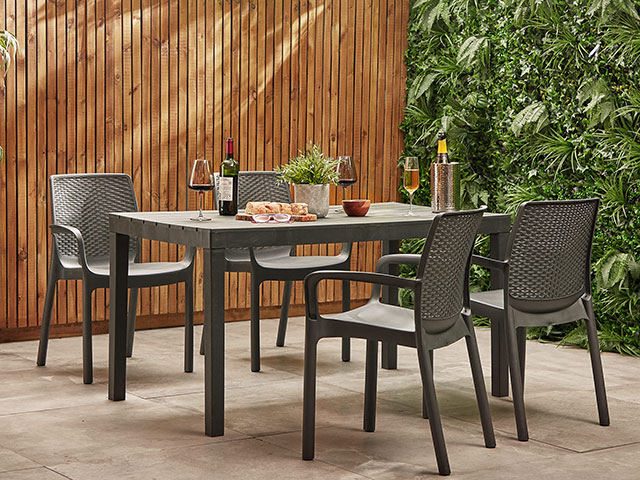 4 piece garden dining set on concrete in front of wooden fence