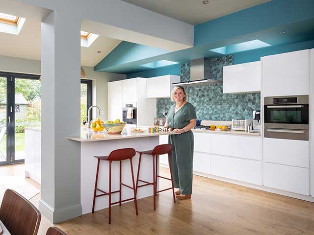 oned kitchen space with island and white units with green hexagonal wall tiles