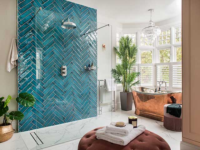 Colourful spacious bathroom with blue tiled shower wall and copper freestanding bath of late Victorian detached home