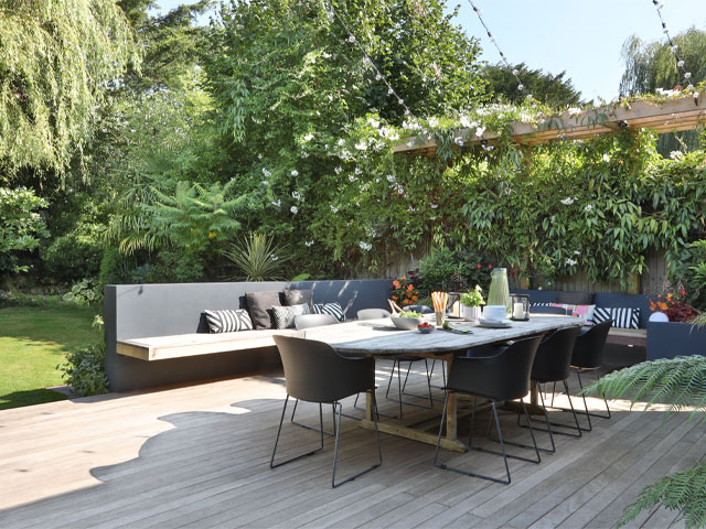 subtropical garden design makeover with decked area, large dining table, bench seating and lush plants