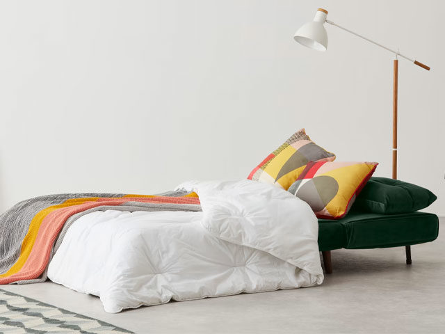 dark green guest bed from Made.com with colourful cushions and modern lamp