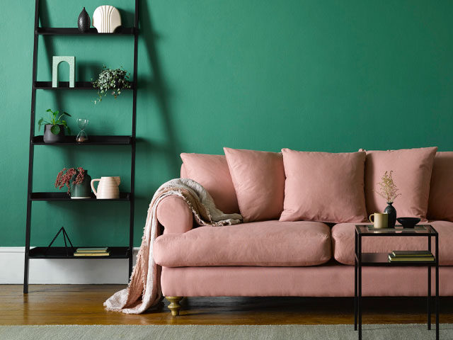 comfy pink sofa with plump feather back cushions and wooden legs